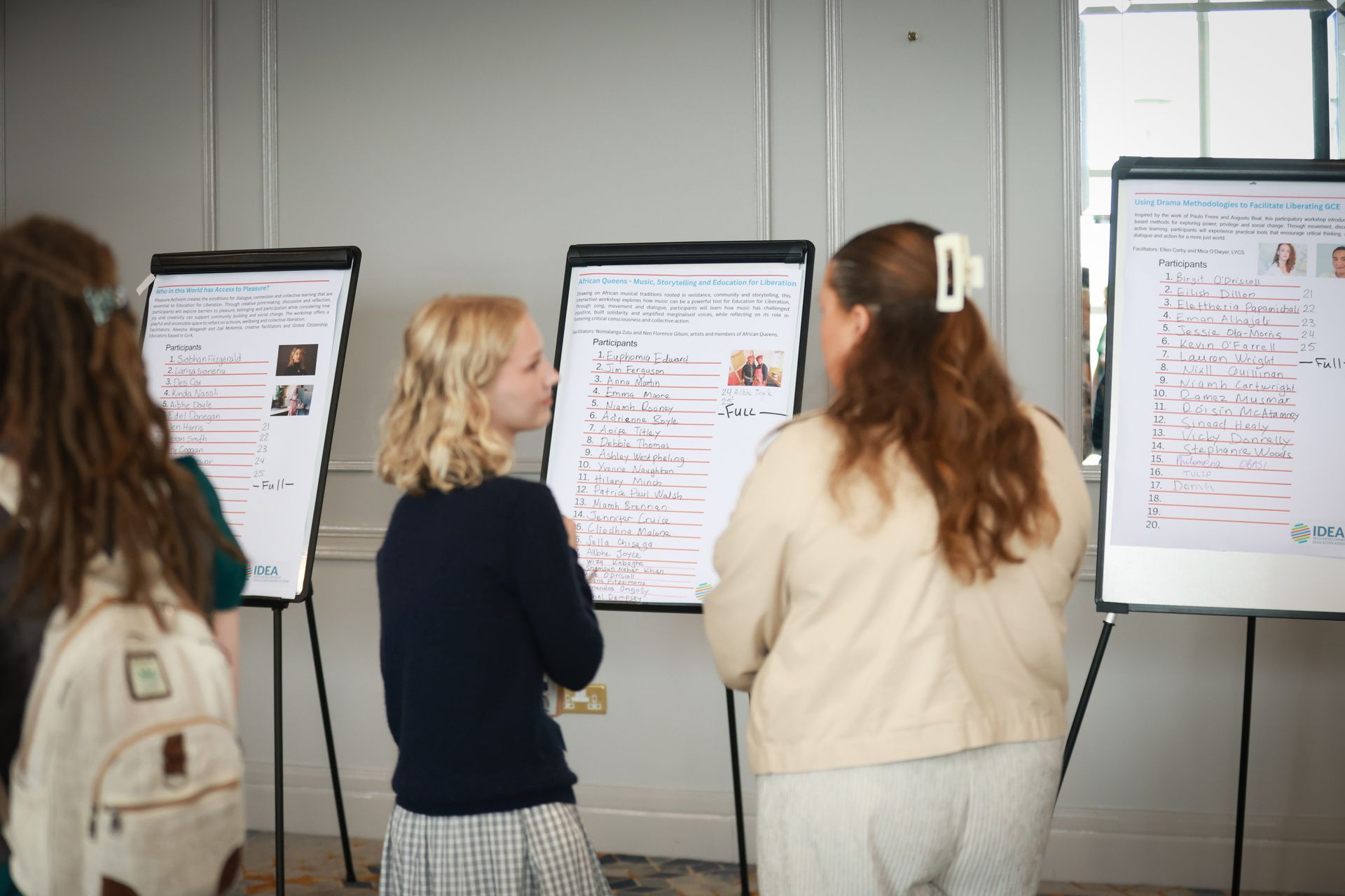 People viewing poster boards in a meeting room, with papers and notes on easels.