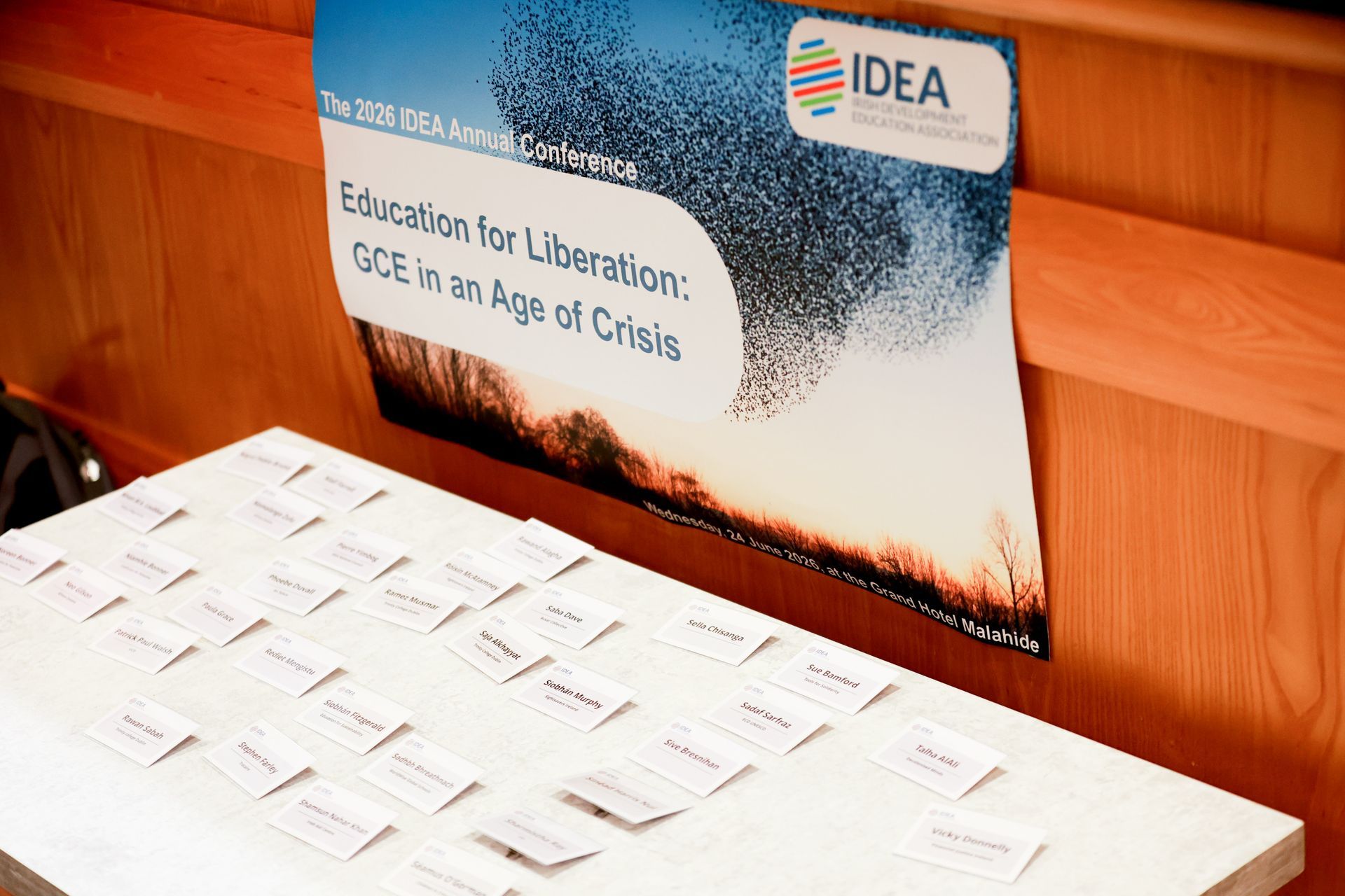 Conference table with name cards and a poster reading “Education for Liberation: GCE in an Age of Crisis.”