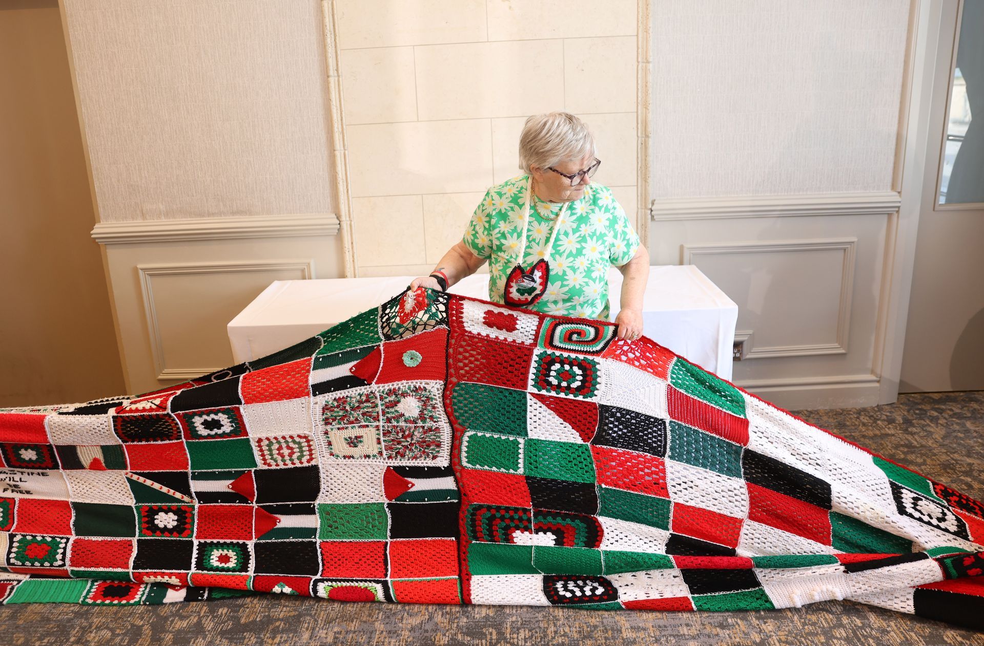 Woman holding a red, green, and black quilt indoors