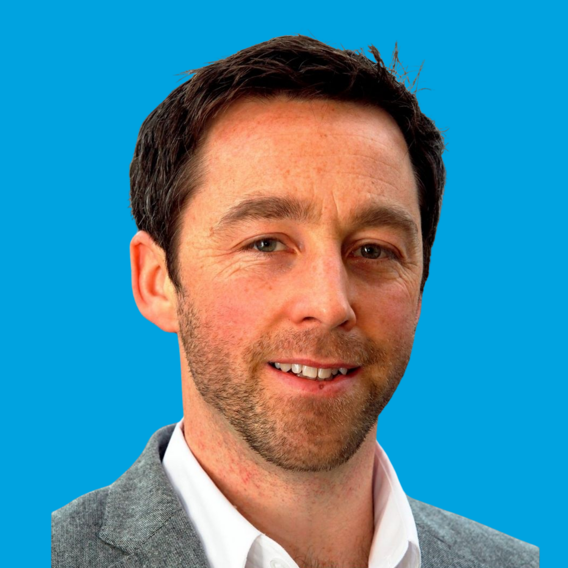 Portrait of a smiling man in a gray blazer against a bright blue background