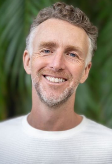 Smiling man in a white shirt against a blurred green background