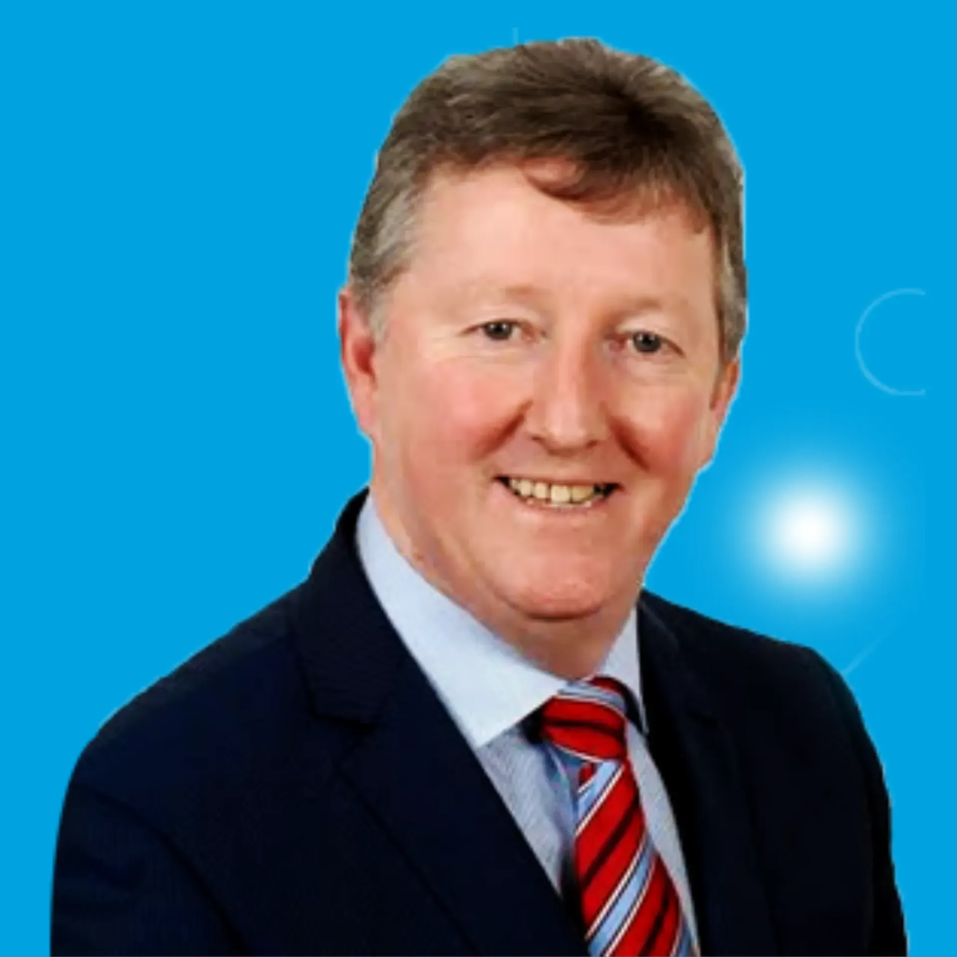 Portrait of a smiling man in a dark suit and red striped tie on a blue background