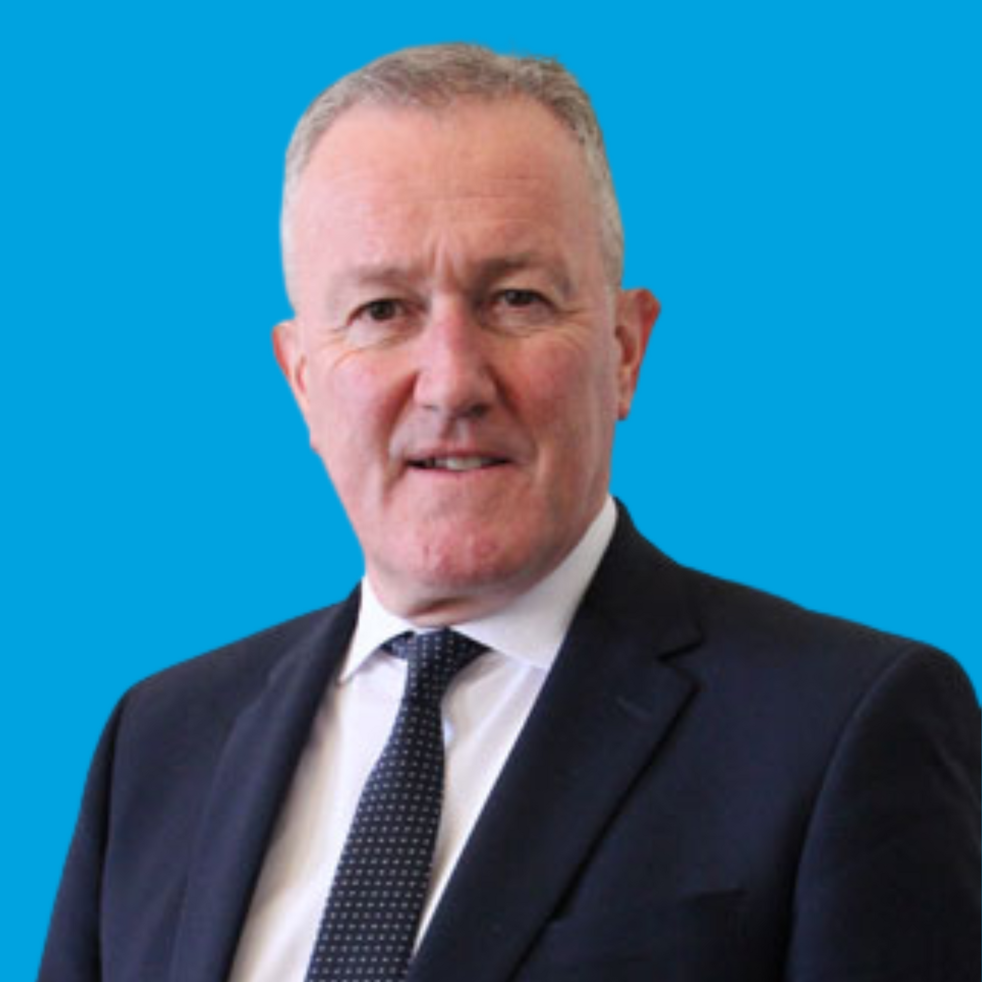 Portrait of a man in a dark suit and tie against a bright blue background