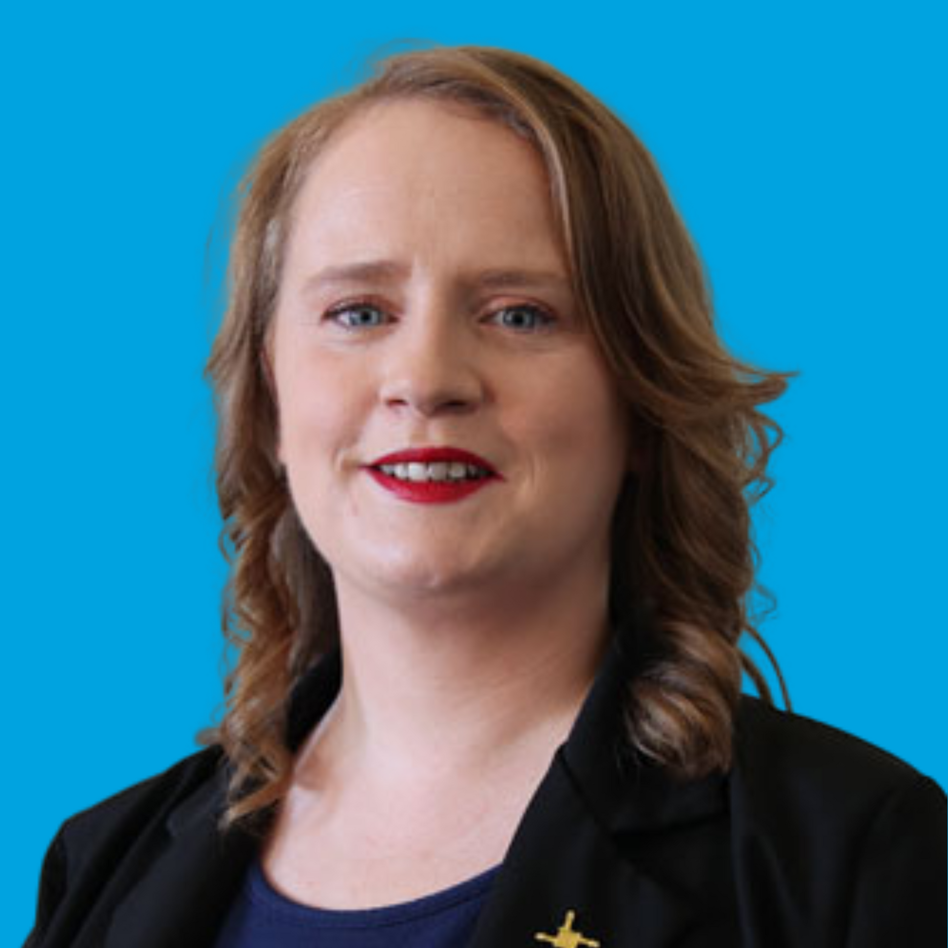 Portrait of a person with shoulder-length hair and red lipstick, wearing a black blazer on a blue background