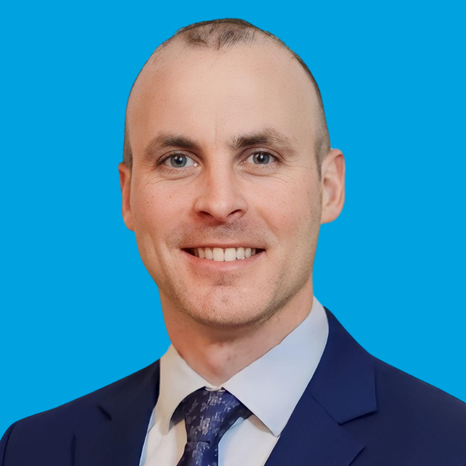 Portrait of a smiling man in a navy suit and tie against a bright blue background