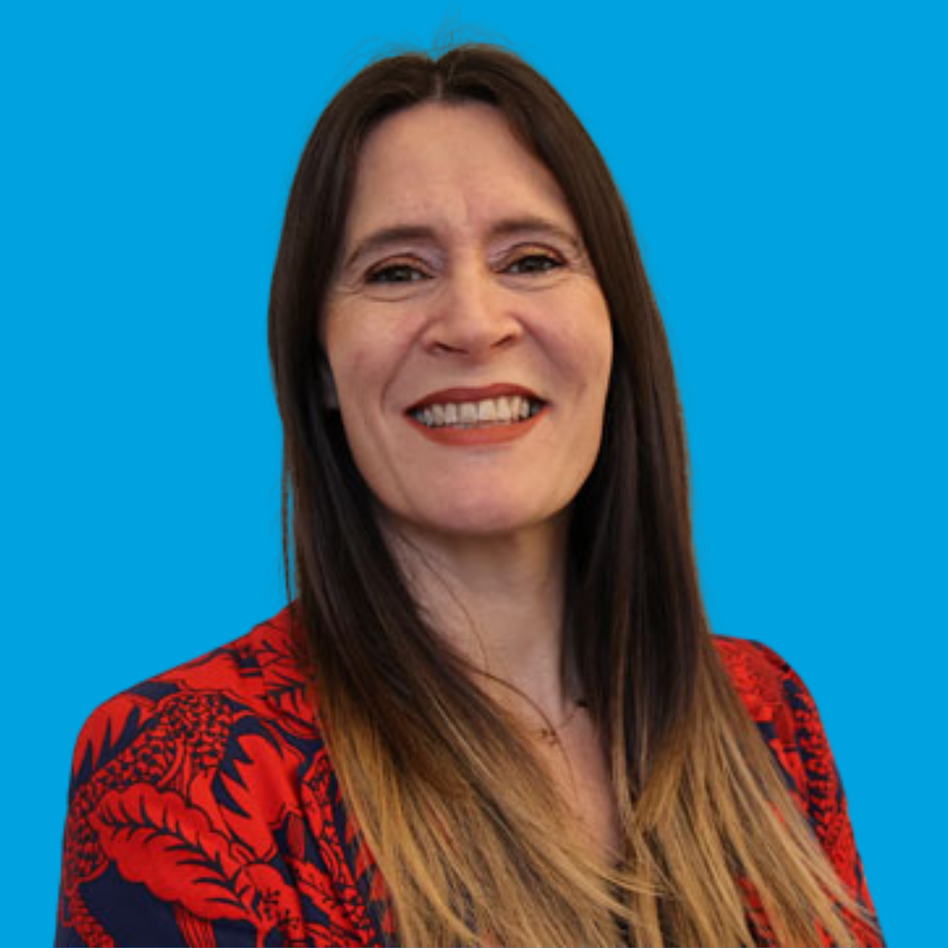 Smiling woman in a red floral top against a bright blue background