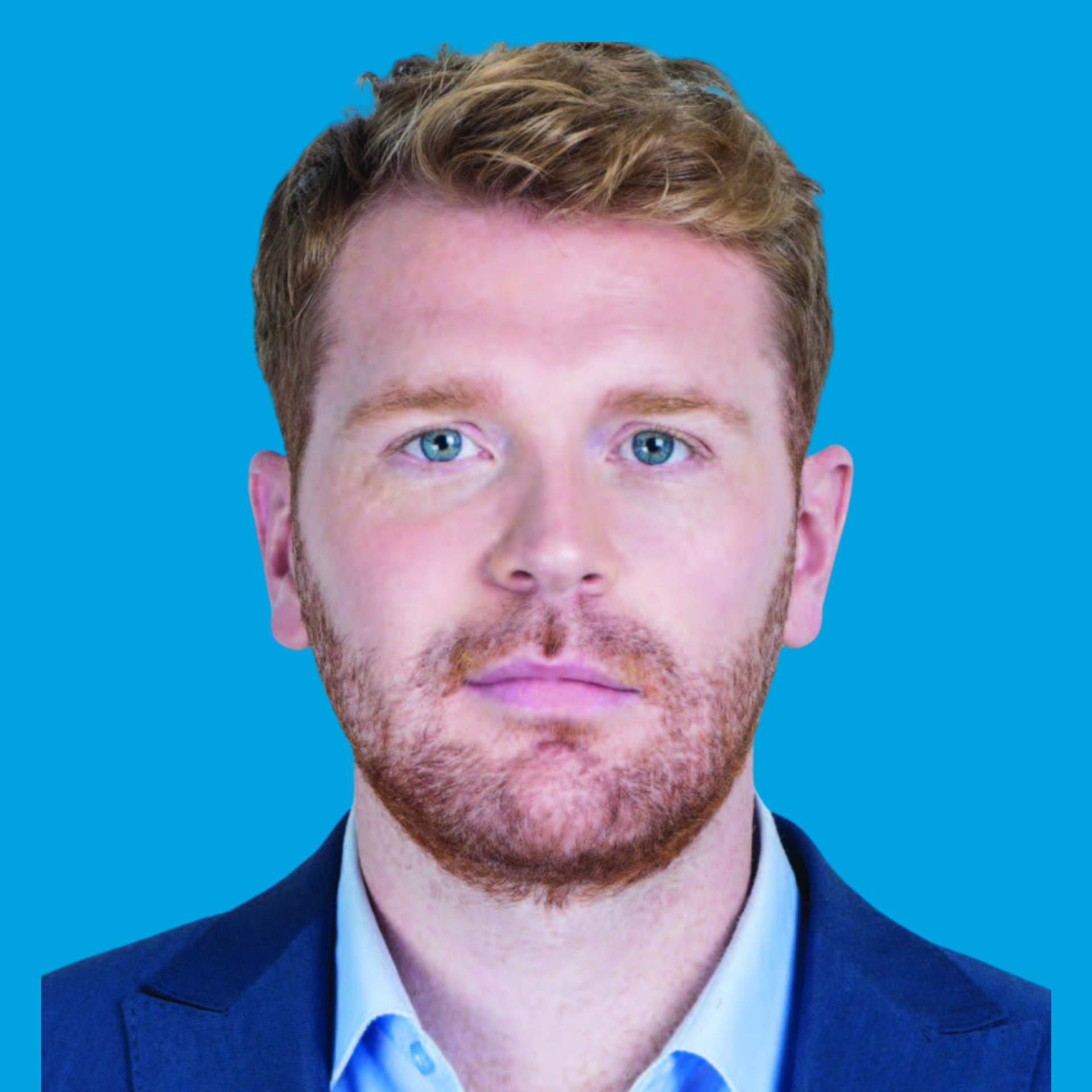 Headshot of a man with red hair and beard wearing a blue blazer against a bright blue background