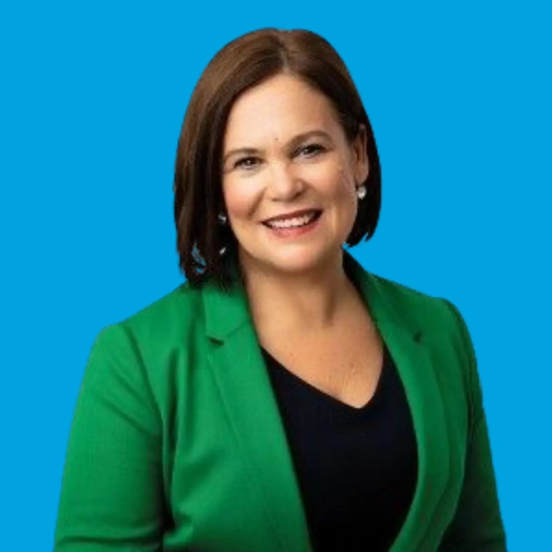 Smiling woman in a green blazer against a bright blue background