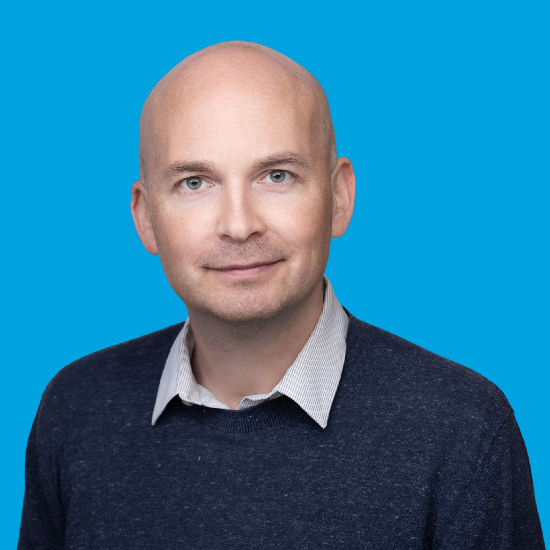 Portrait of a bald man in a dark sweater against a bright blue background