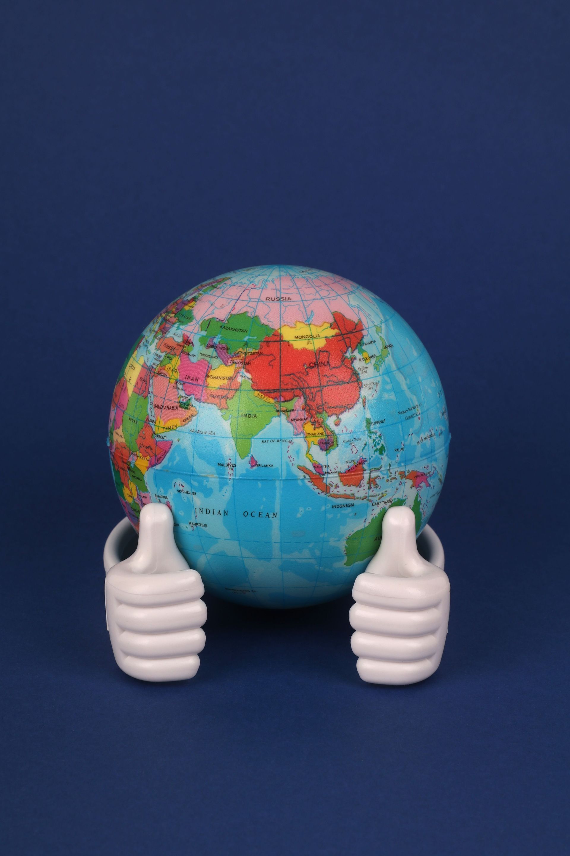 Globe held by two white hands against a dark blue background