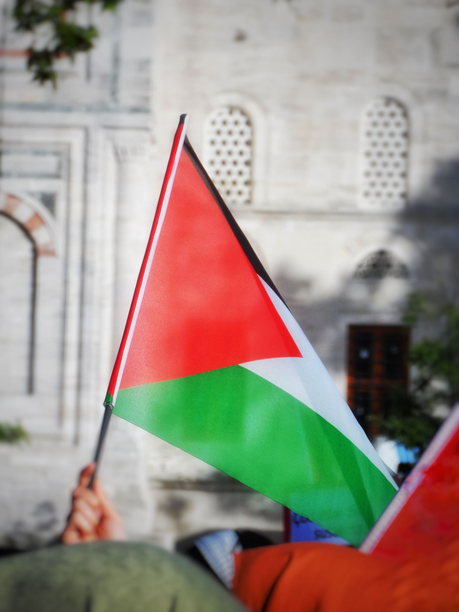 Palestinian flag waving in front of a stone building