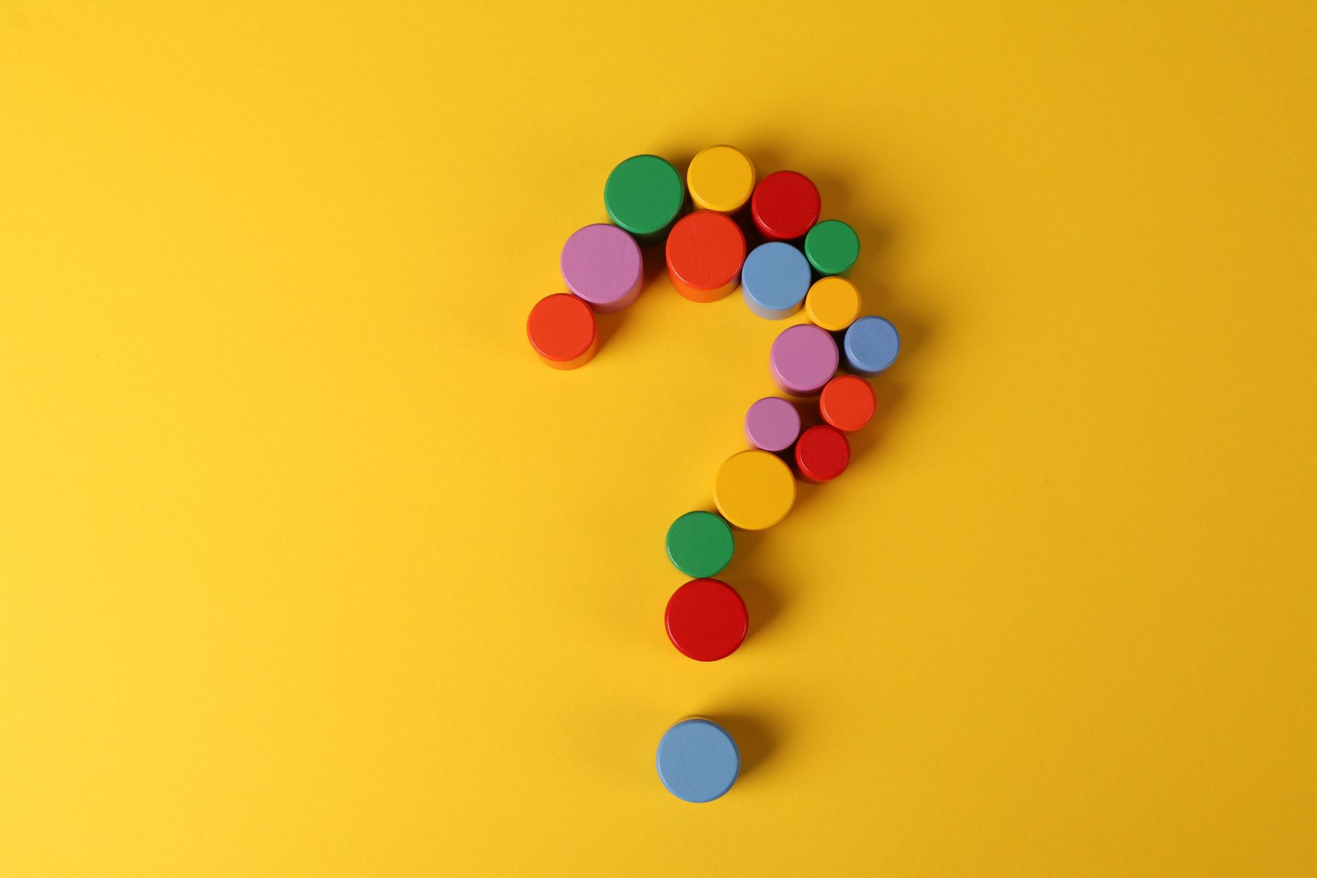 Colorful dots arranged into a question mark on a bright yellow background