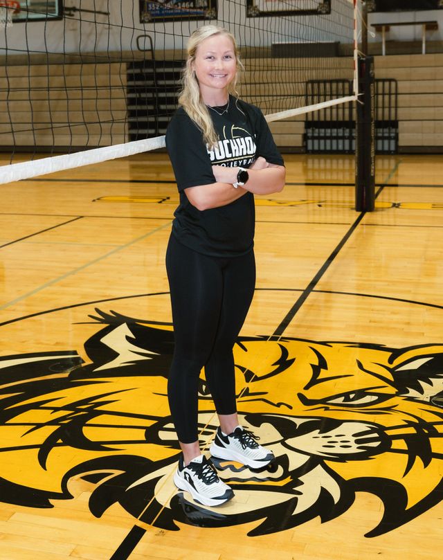 Smiling person in a black UCHHOLZ volleyball shirt against a plain beige wall