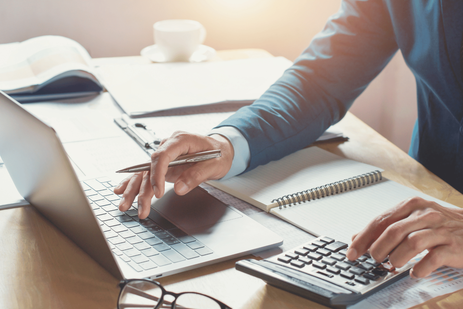 A man is using a laptop and a calculator at the same time.