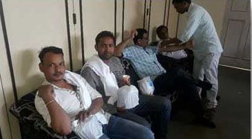 A group of men are sitting on a couch in a room.