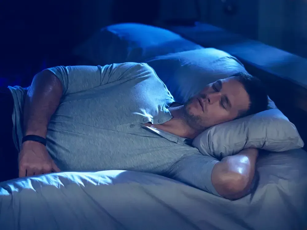 a man in a grey shirt is sleeping on a bed