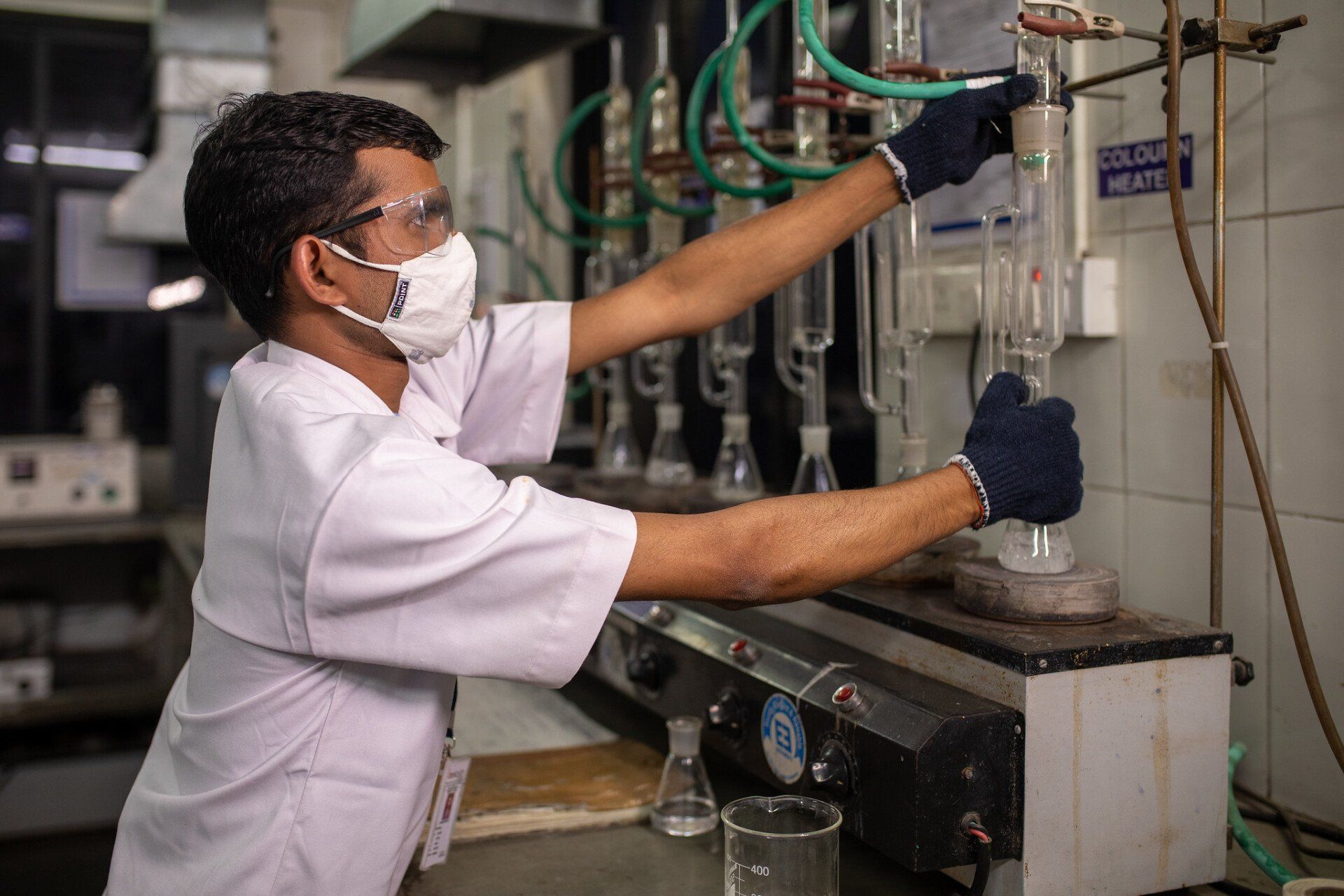 A man wearing a mask and gloves is working in a lab.