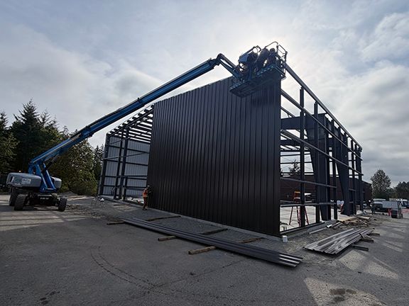 Construction crews continue to add exterior wall panels to metal building frame