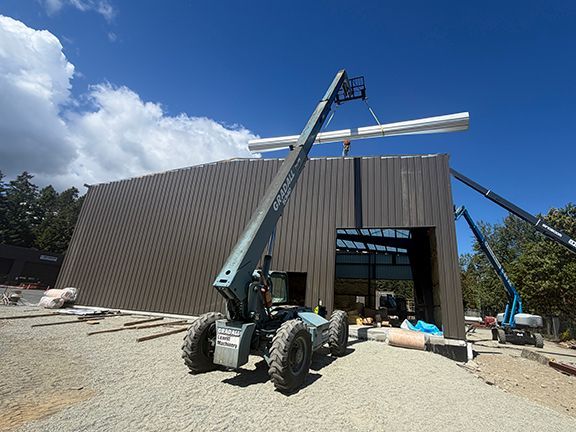 Metal roofing panels being added to construction site using lift.