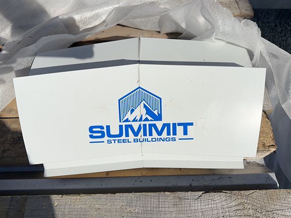 Metal building ridge cap with Summit Steel Buildings logo