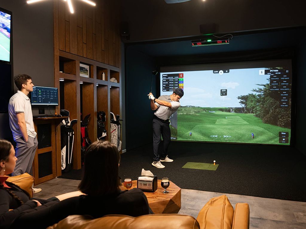Friends enjoy a game of indoor golf using a simulator