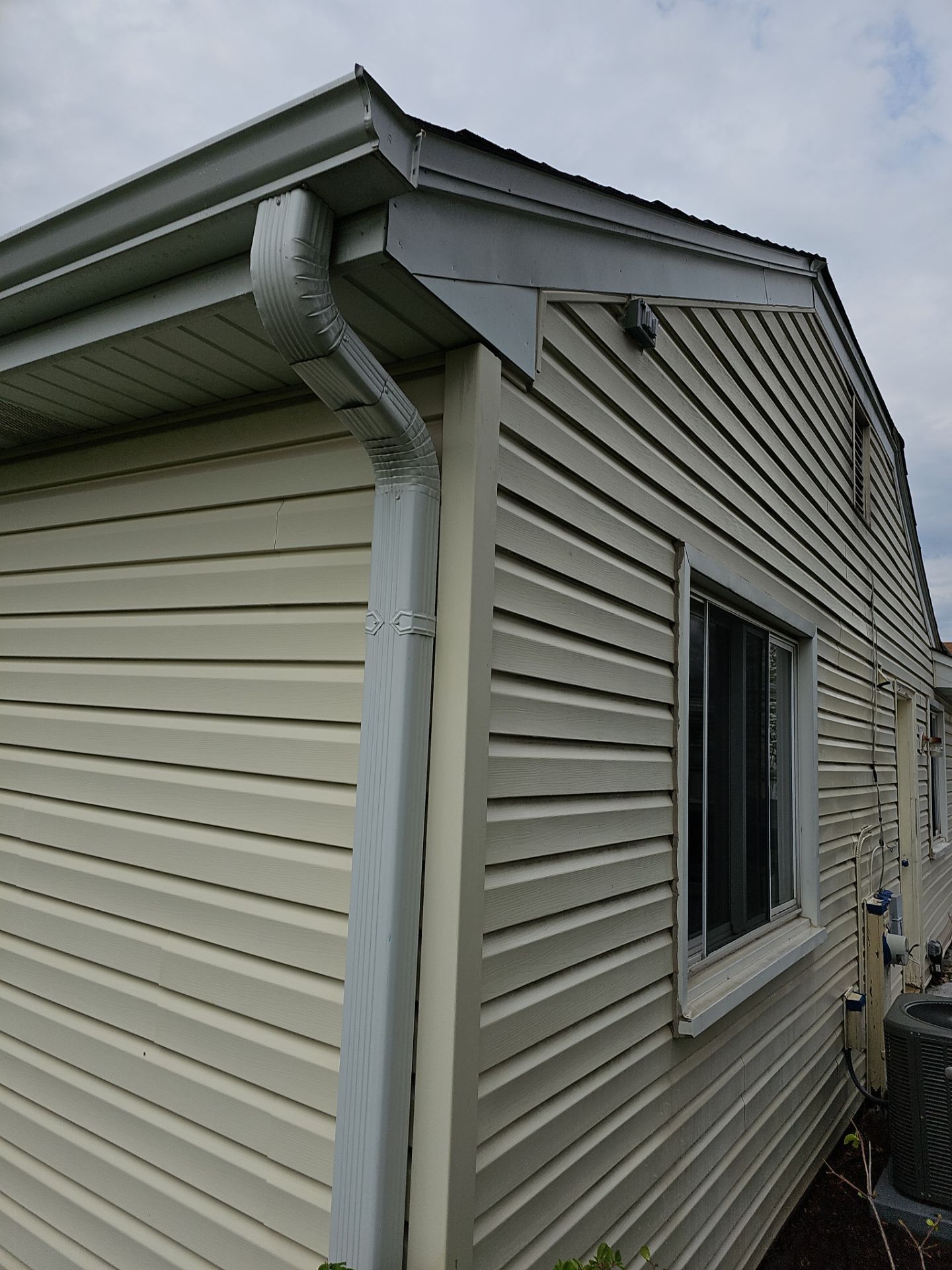 A house with a gutter on the side of it and a window.