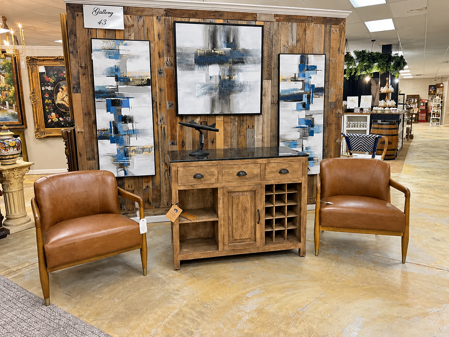 Furniture showroom display with leather chairs, rustic wood cabinet, and blue abstract wall art
