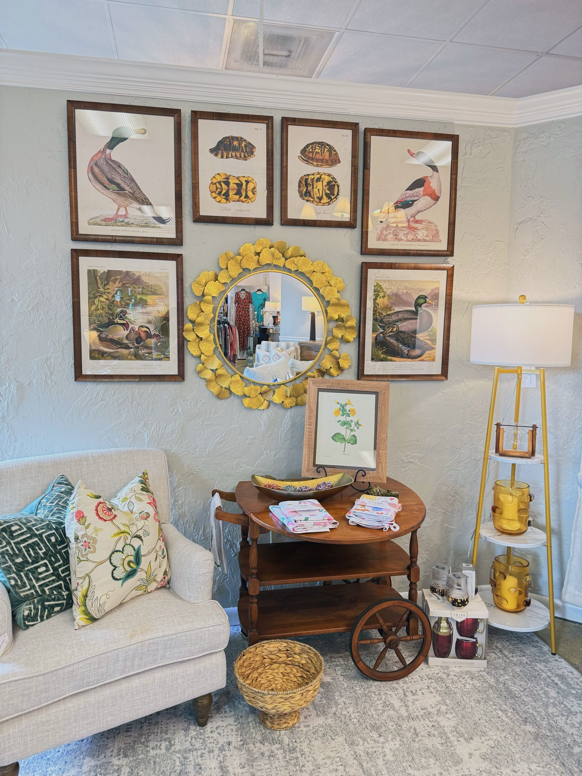 Cozy living room corner with framed art, gold mirror, white sofa, side table, and floor lamp