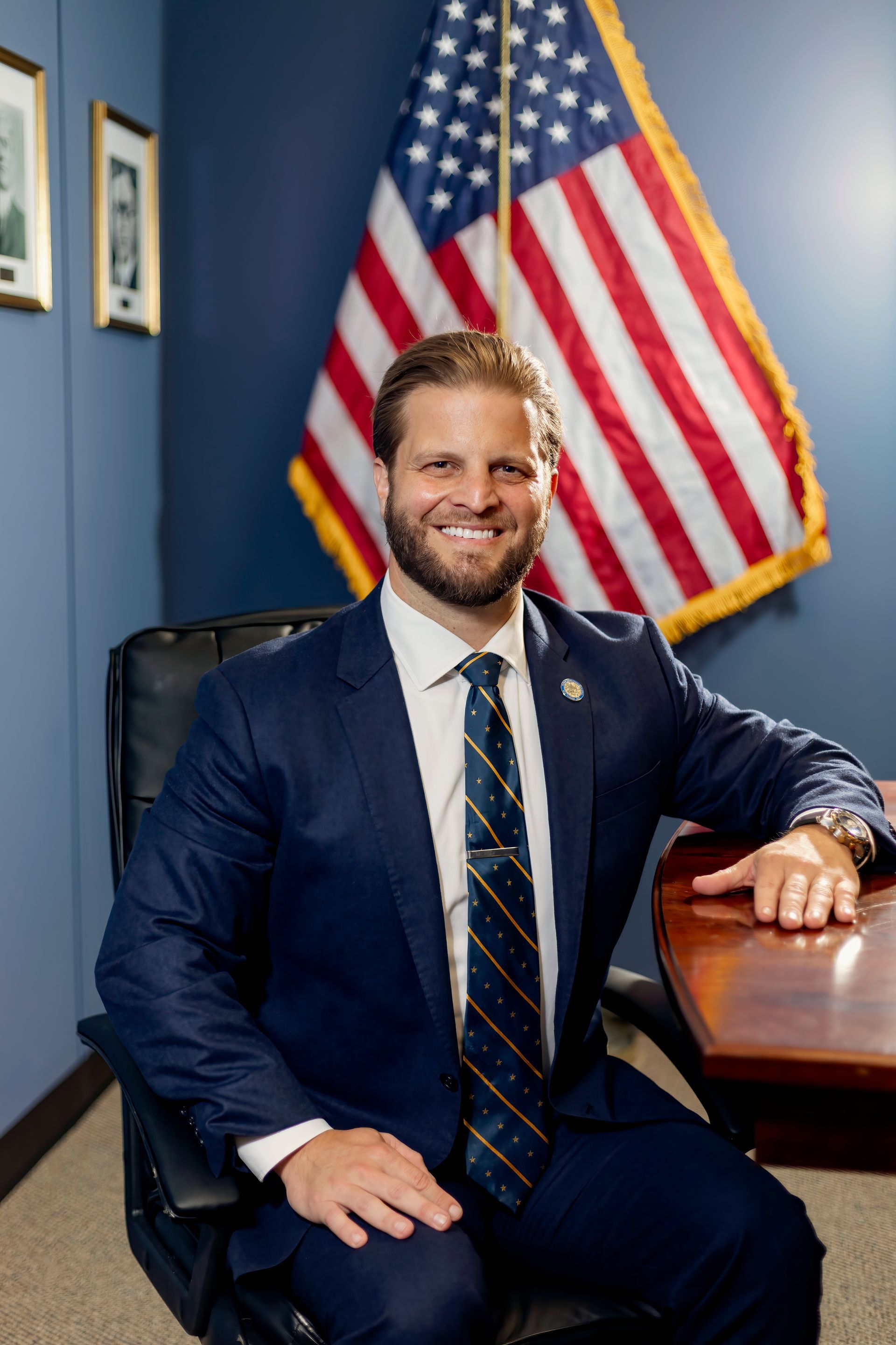 A man in a blue suit and red tie is smiling for the camera.