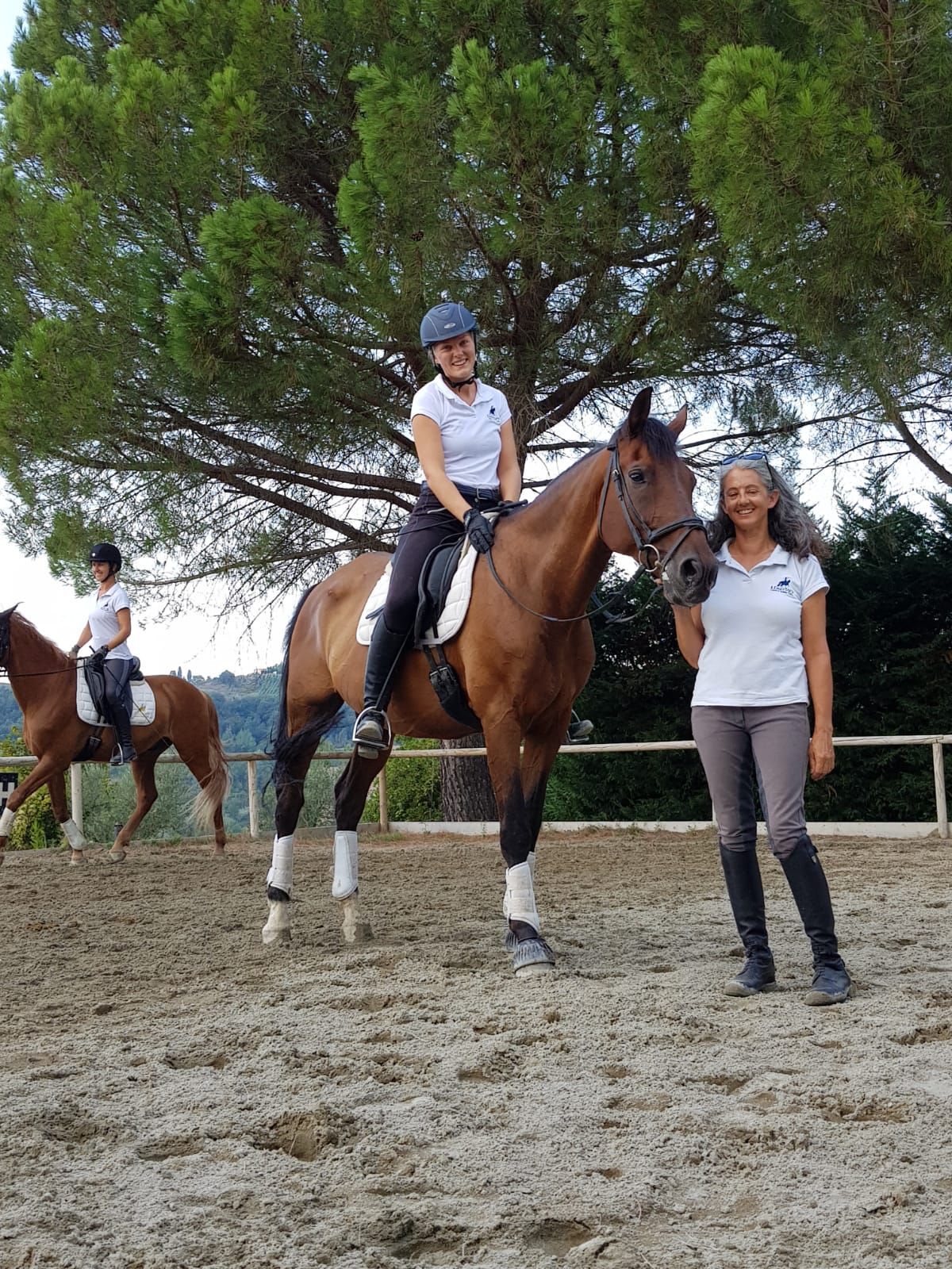 A woman is riding a horse next to another woman standing next to a horse.