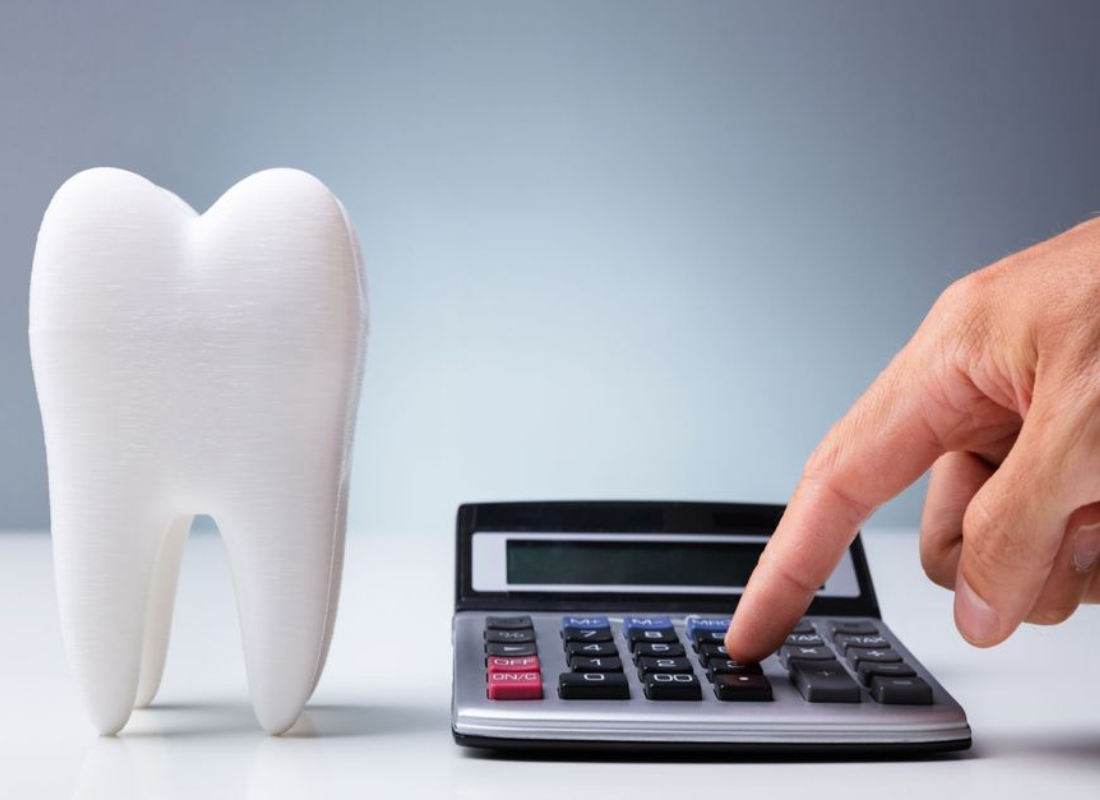 a person is using a calculator next to a model of a tooth