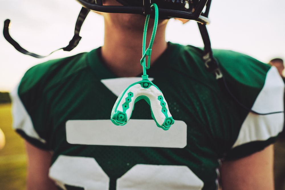 a football player with a dental sport mouth guard attached to his helmet