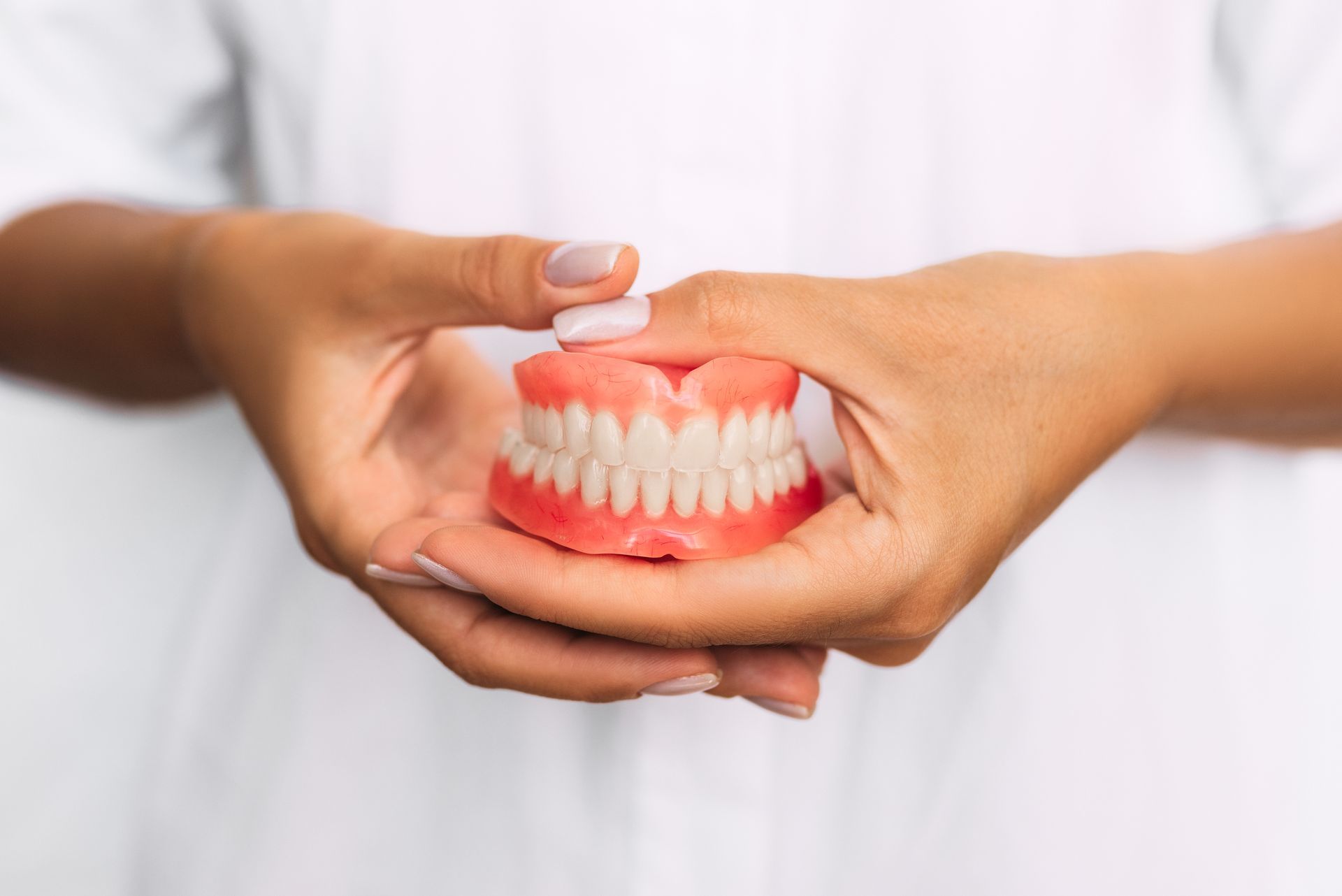 a woman is holding a denture in her hands
