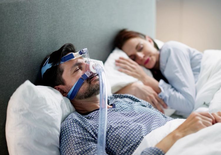 a man is sleeping in a bed with an oxygen mask on his face .