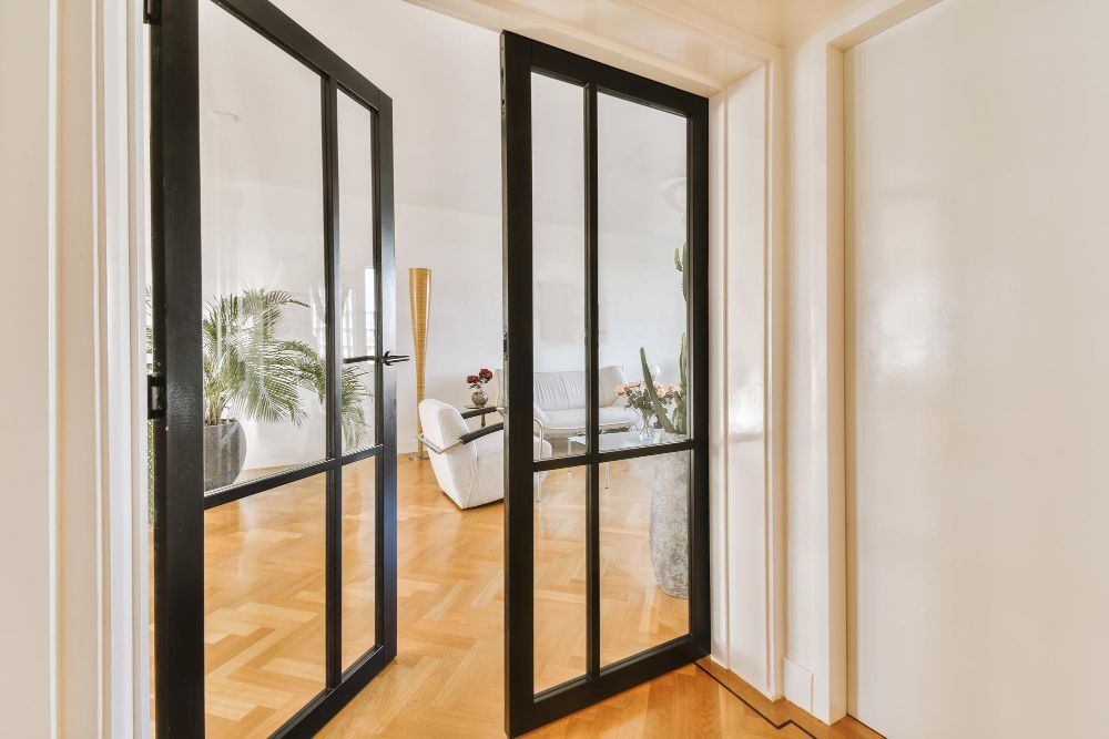 A hallway in an office building with sliding glass doors and a chair.