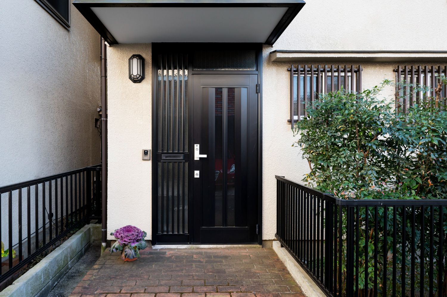 The front door of a house with a black door and a black fence.