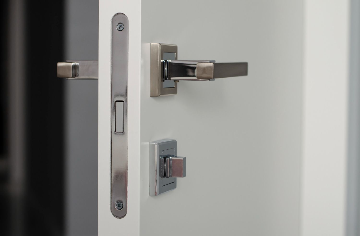 A close up of a door handle on a white door.
