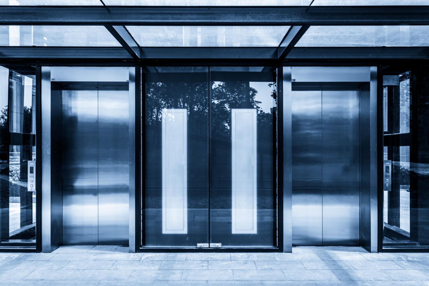 A row of stainless steel elevators in a building.