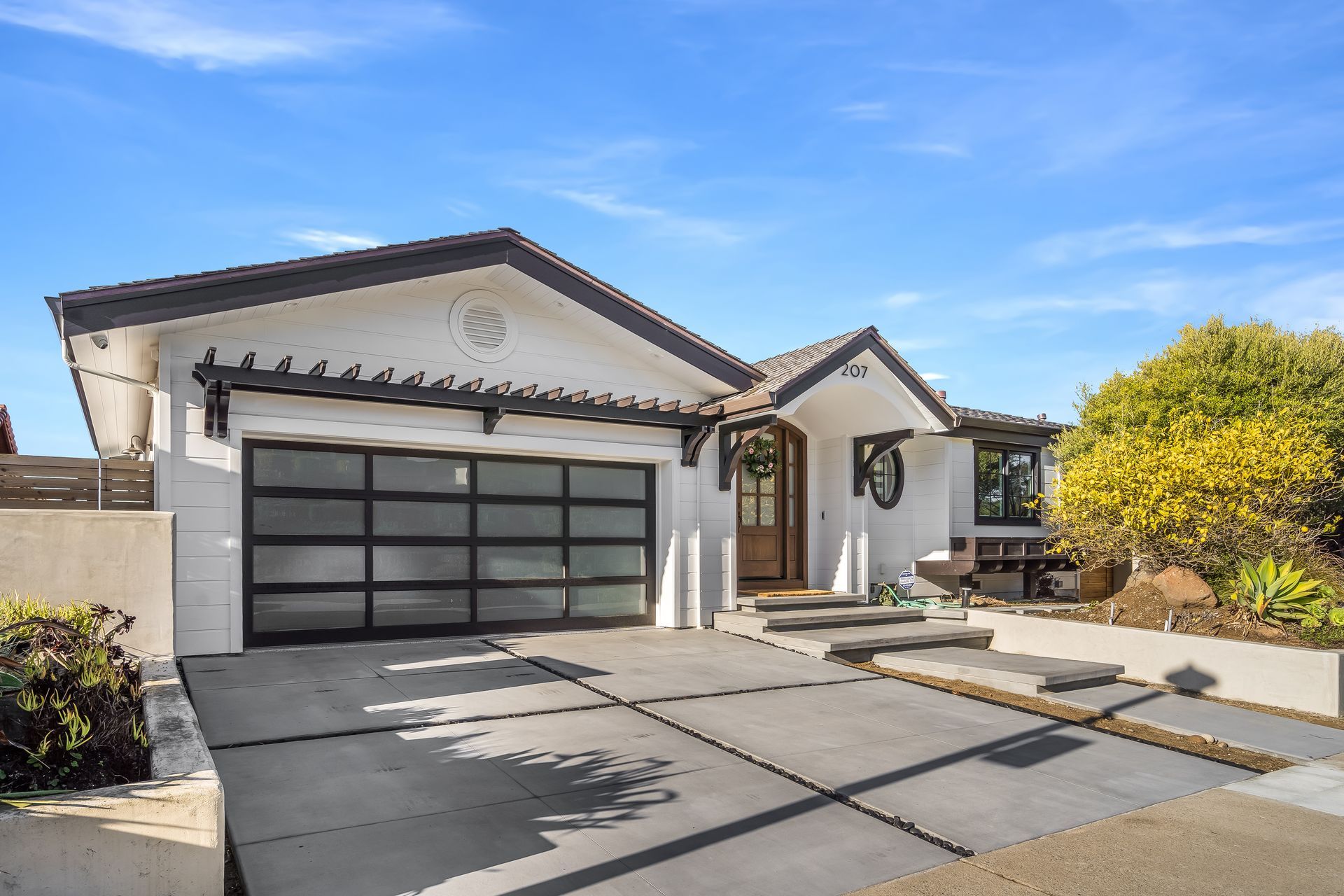 A white house with a black garage door is for sale.