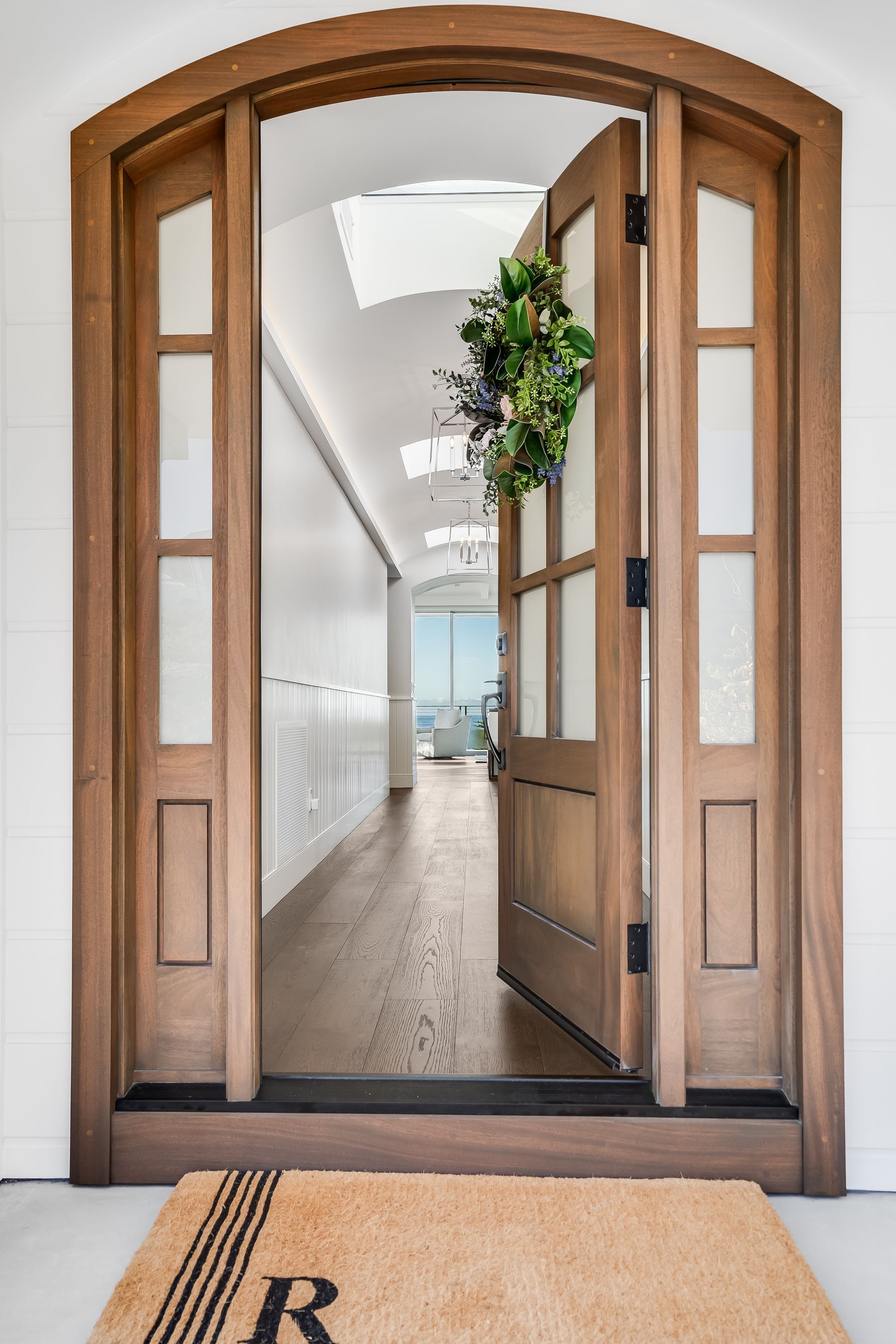 A door with a wreath on it and a welcome mat with the letter r on it