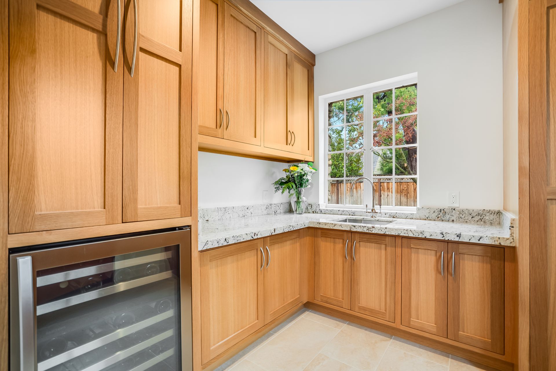 A kitchen with wooden cabinets , granite counter tops , and a wine cooler.