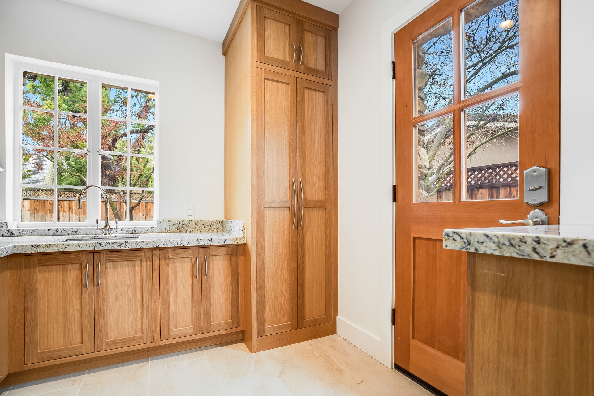 A kitchen with wooden cabinets , a sink , and a door.
