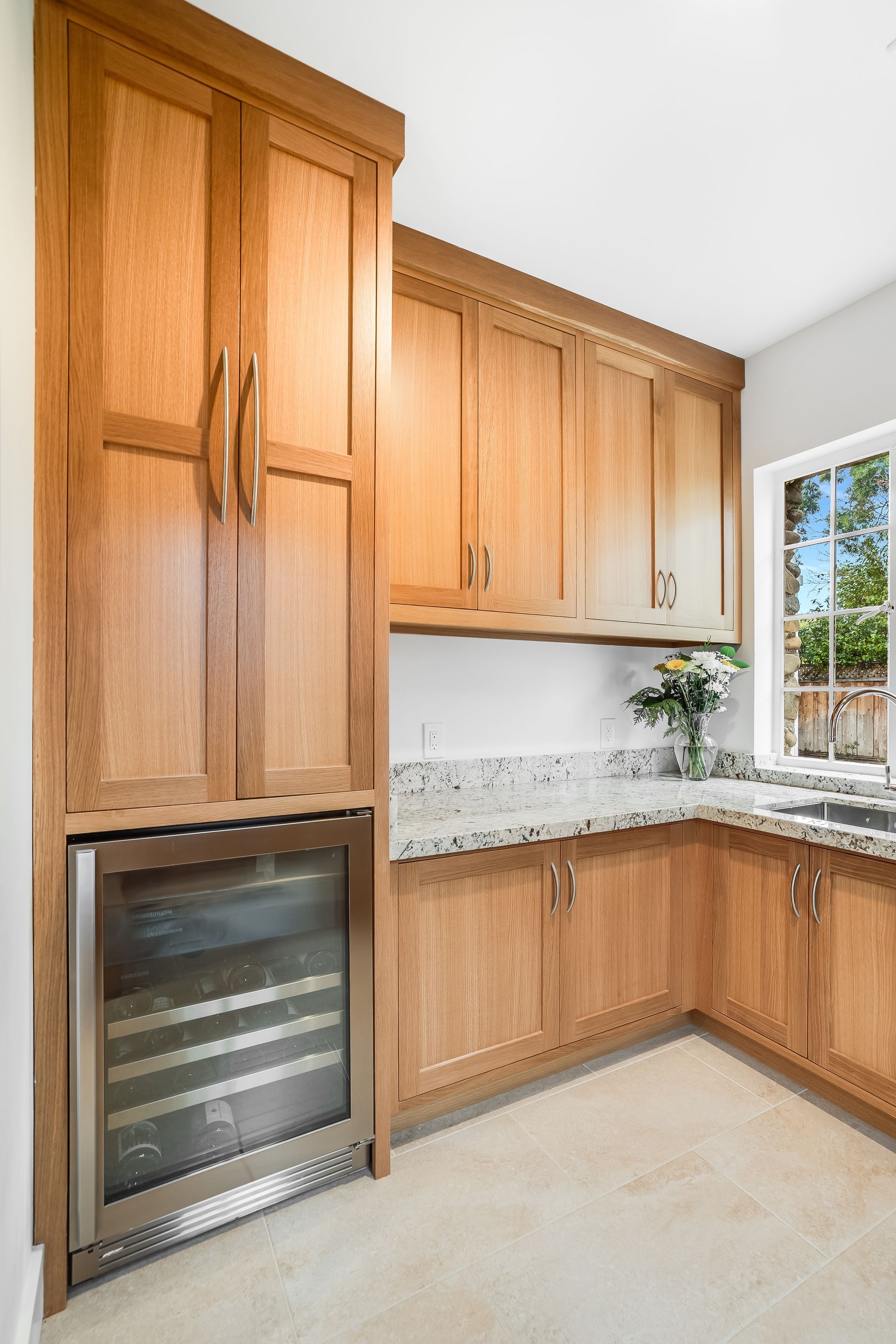 A kitchen with wooden cabinets and a wine cooler.