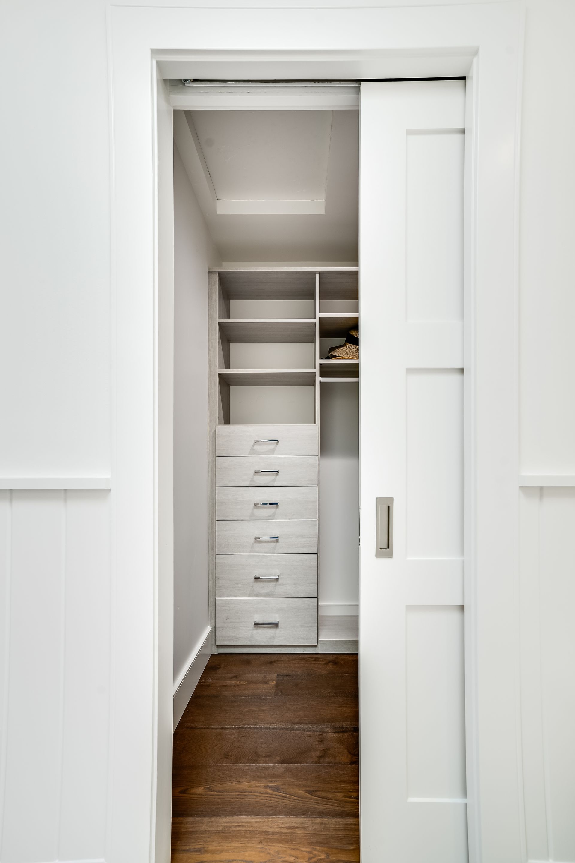 A walk in closet with sliding doors and drawers.