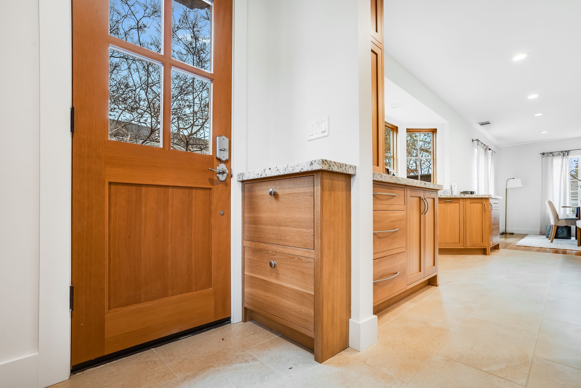 A wooden door is open to a kitchen with wooden cabinets.