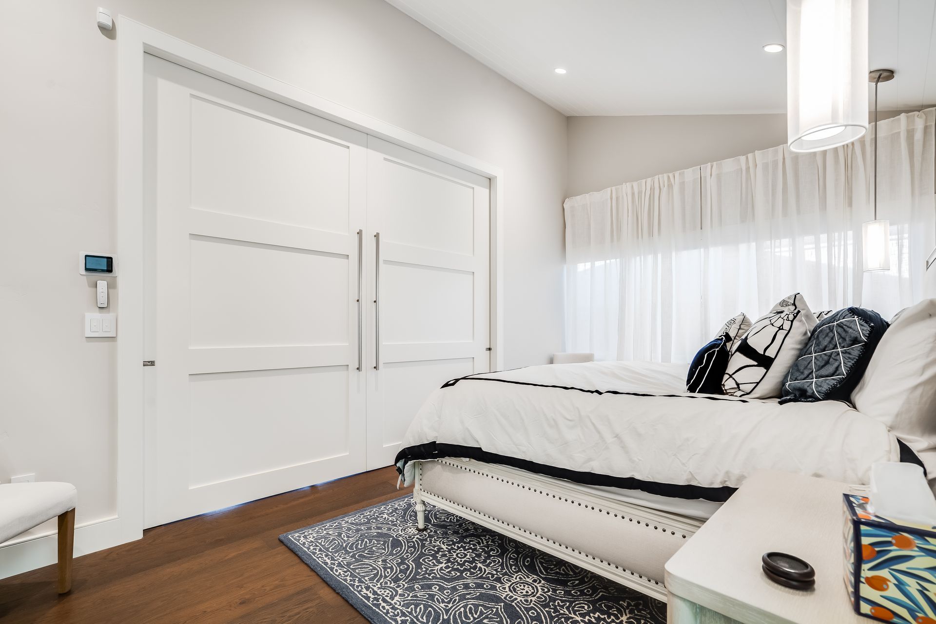 A bedroom with a bed , nightstand , rug and window.
