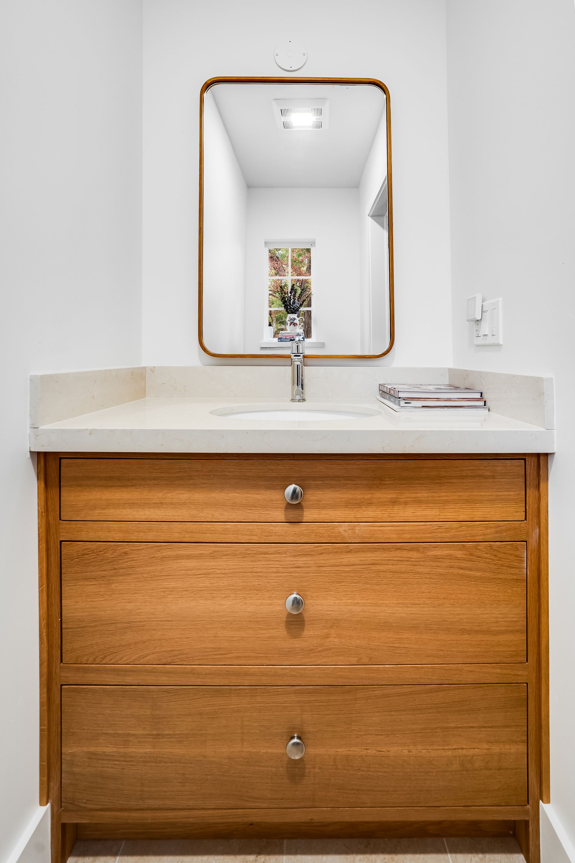A bathroom with a wooden vanity and a mirror.
