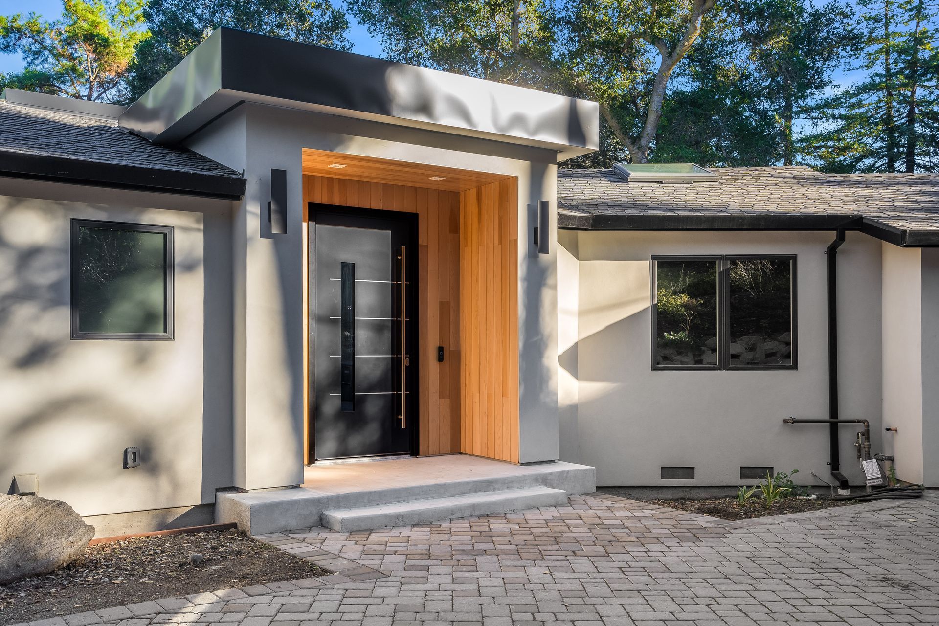 The front of a house with a black door and a brick driveway.