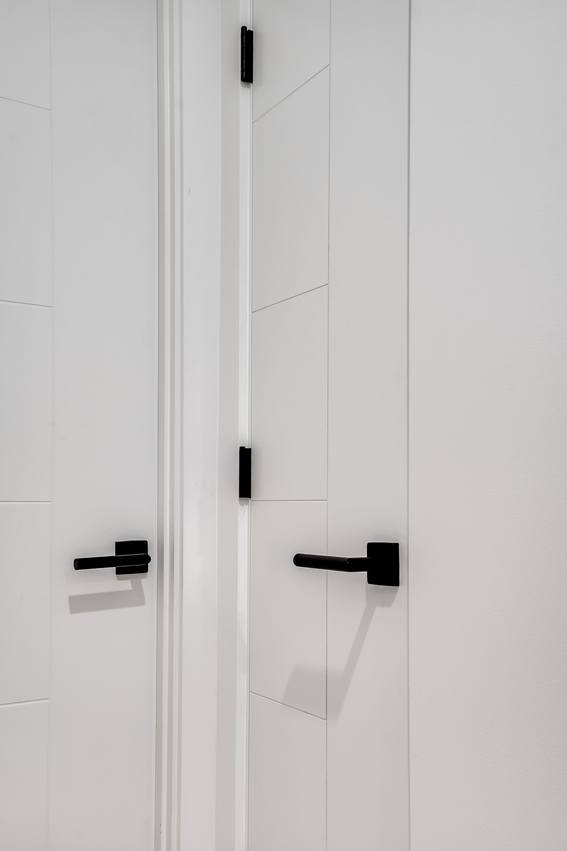 A close up of a white door with black handles.