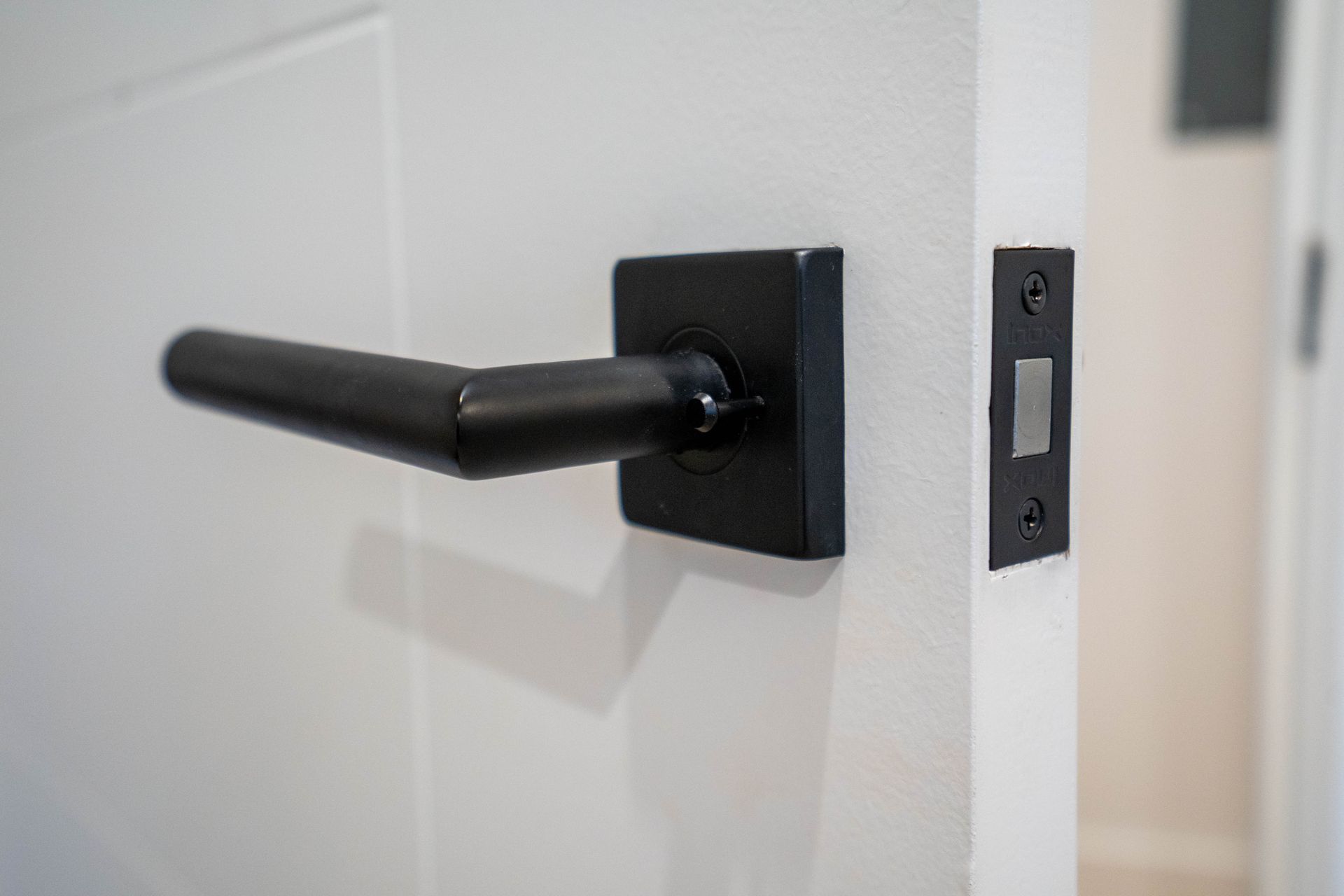 A close up of a black door handle on a white door.